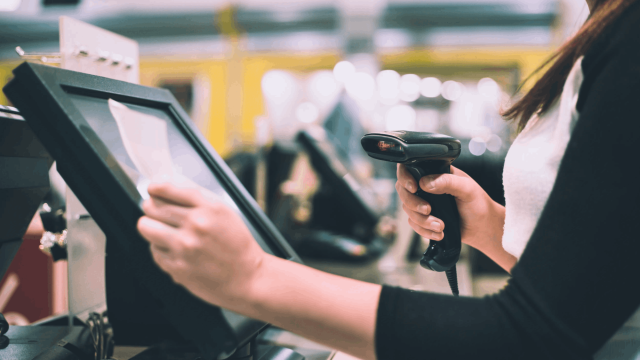 Cajera usando lector de códigos en sistema de punto de venta POS en tienda retail.